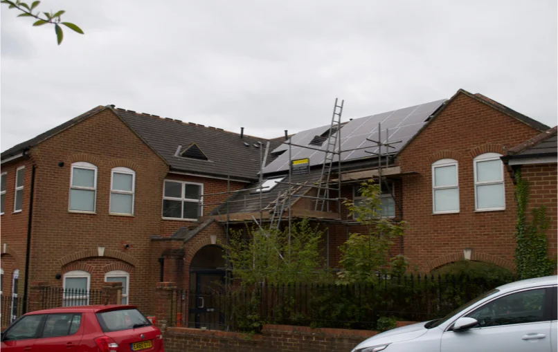 This image depicts a building which was retrofitted from offices into 6 new residential flats with large solar panels mounted on the roof.