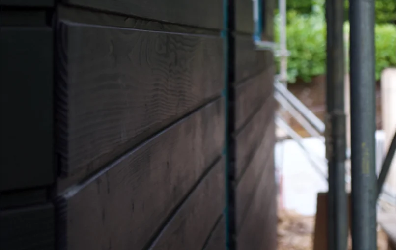 This image depicts a close up shot of some black wooden cladding which was used on the new houses from the rear.